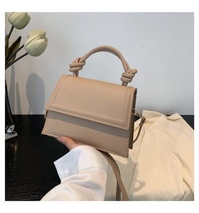 Detail of beige leather handbag with unique knotted handles and rectangular flap design