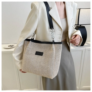 Detail of hollow woven tote bag with black leather trim and silver chain shoulder strap