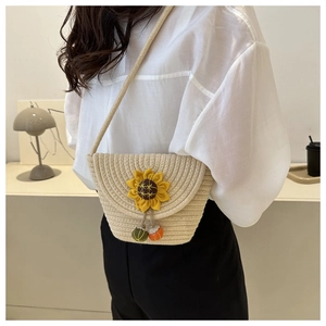 Détail du sac bandoulière en paille tissé avec décor de tournesol et pendentifs colorés