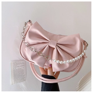 Détail du sac à main rose avec nœud, perles et chaîne métallique à fleurs chic