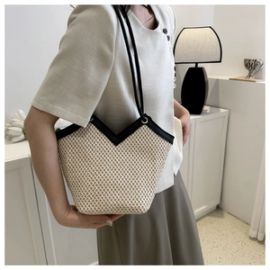 Détail du cabas en paille tressée avec bordure en cuir noir et passepoil élégant en V