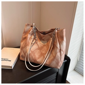 Detail of vintage brown tote bag with quilted pattern and metal chain leather strap