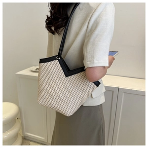 Détail du sac cabas en paille tissée avec anses en cuir noir et ouverture élégante en V