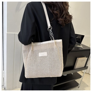 Detailed view of cream woven tote bag with leather strap and silver metal chain link