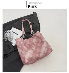 Detail view of pink quilted tote bag with chain strap and fashion label on white surface