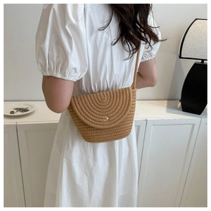Détail d'un sac bandoulière tissé marron chaud avec boucle dorée et texture circulaire