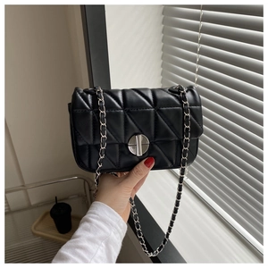 Close-up of black quilted leather shoulder bag featuring a silver twist lock and chain strap