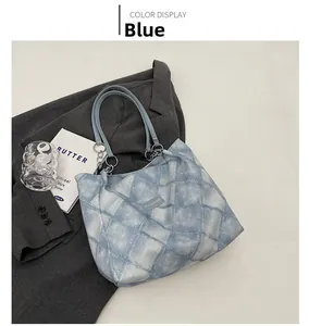 Close-up of blue quilted denim tote bag with chain strap and fashion label detail