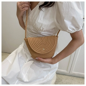 Gros plan détaillé d'un sac bandoulière en paille tressé main avec boucle dorée et sangle