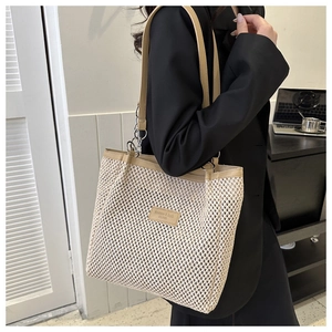Detail of woven tote bag featuring cream mesh texture and brown leather straps for commuting