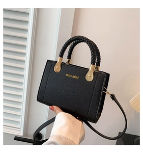 Détail du sac bandoulière en cuir noir avec poignée tressée et logo doré miss.mini