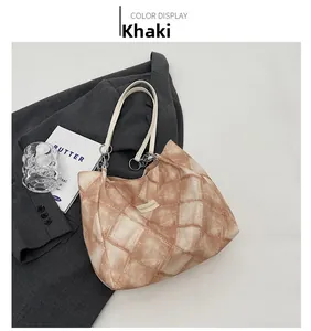 Detail of khaki tote bag with vintage diamond quilt texture and cream handle accents
