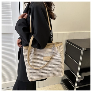 Detail of beige hollow woven tote bag featuring leather shoulder straps and silver chain links