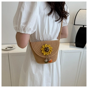 Détail du sac en paille tissé main avec fleur de tournesol et pompons colorés