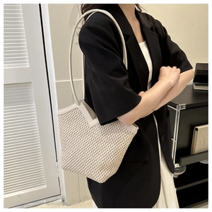 Gros plan sur un sac porté épaule tissé beige avec texture et bordure coupée en V