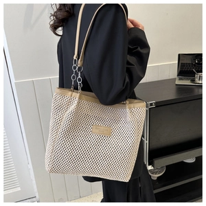 Woven tote bag close-up showing beige texture and leather shoulder strap with chain