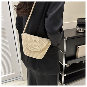 Détail d'un sac bandoulière tissé beige avec boucle dorée et texture de corde tressée