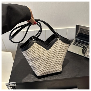 Détail du sac cabas en paille tressée avec bordure en cuir noir et ouverture en V