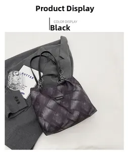 Detail of black tote bag with vintage wash texture and metallic ring hardware on blazer