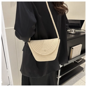 Détail d'un sac en paille tressée beige avec textures spirales et fermoir en métal doré