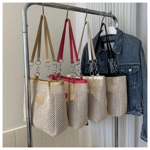 Detailed view of woven tote bags in four colors hanging on a rack for summer fashion