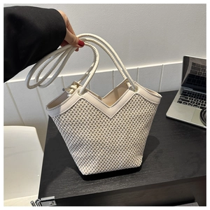 Détail du sac cabas tissé avec ouverture en V et bordure en cuir blanc sur bureau