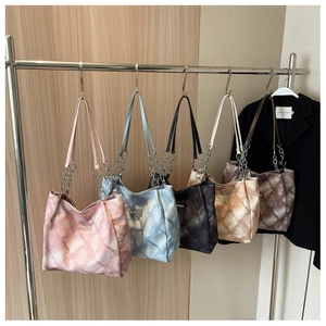 Close-up of quilted tote bags with chain straps in five gradient colors on a rack