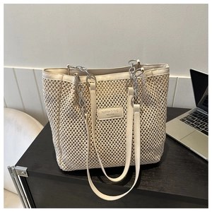 Detail of beige woven tote bag with hollow mesh texture and faux leather trim