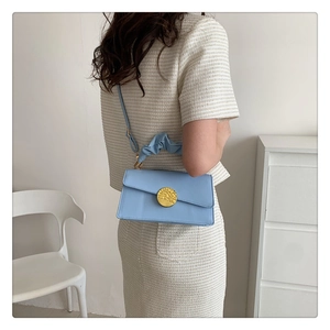 Detail of light blue square handbag with gold buckle and pleated handle wrap
