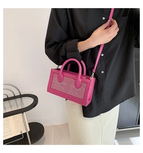 Détail d'un sac à main fuchsia orné de strass brillants avec des boucles en métal doré