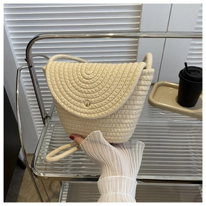 Détail du sac seau en paille avec texture en corde tressée et bouton doré élégant