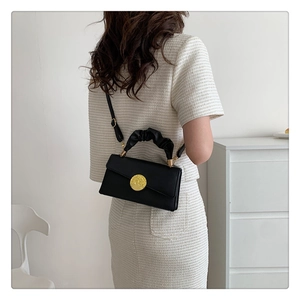 Close-up of black pleated handle handbag with elegant gold metal decorative buckle