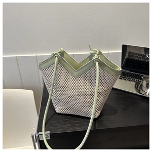 Détail du sac cabas tissé avec texture beige et bordure en cuir vert clair en forme de V