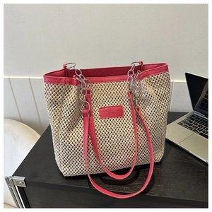 Detail of woven straw tote bag with pink PU trim and silver metal chain strap