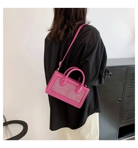 Sac à bandoulière fuchsia avec strass brillants porté par un mannequin à l'épaule