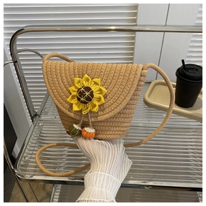 Détail du sac bandoulière en paille avec fleur de tournesol et pompons colorés