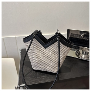 Détail du sac seau tissé beige avec bordures en cuir noir et fine bandoulière noire