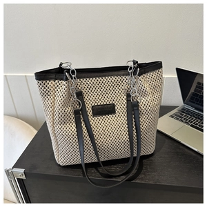 Detail of off-white woven tote bag with black leather trim and silver chain shoulder strap