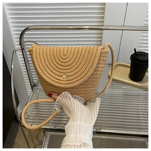 Détail d'un sac bandoulière en paille tressée kaki avec fermoir doré et bandoulière corde