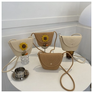 Vue détaillée de mini sacs bandoulière tissés avec breloques tournesol sur table blanche