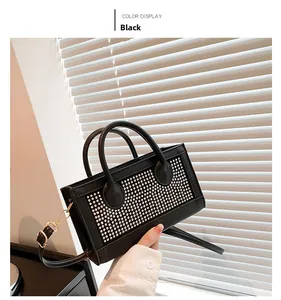 Detail of black rectangular handbag featuring silver studs and detachable shoulder strap