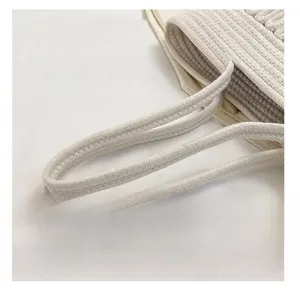 Detailed macro view of woven shoulder straps on a minimalist beige straw tote bag