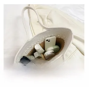Detail view of woven tote interior holding smartphone, umbrella, and cosmetics