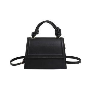 Minimalist black leather crossbody bag with knot handle and adjustable strap on white background