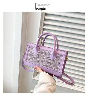 Close-up of a purple rhinestone handbag featuring dual handles and adjustable shoulder strap