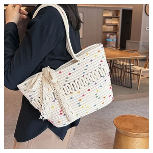 Detail of hand-woven straw tote bag with colorful polka dots and white lace bow accessory