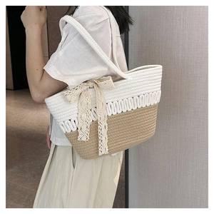 Detail of handwoven straw tote bag featuring contrast colors and delicate lace bow