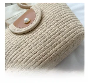 Détail d'un sac cabas tissé avec un rabat en cuir marron et un ornement perle