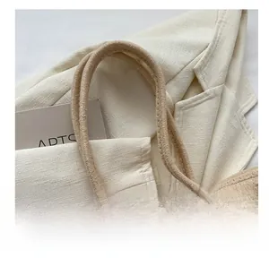 Détail d'un sac cabas tissé beige avec anses en corde douce et accessoires de décoration