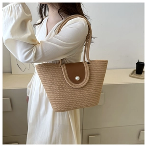Détail du sac cabas en paille tressée avec rabat en cuir et grand fermoir perle